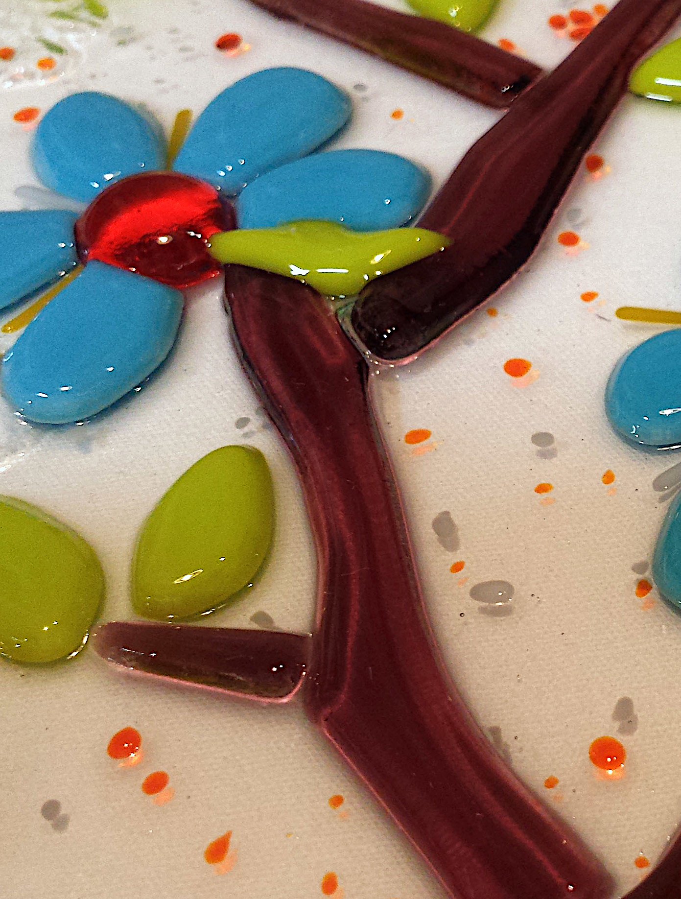Fused glass: close up image of a window panel featuring a botanical design of a dogwood flower